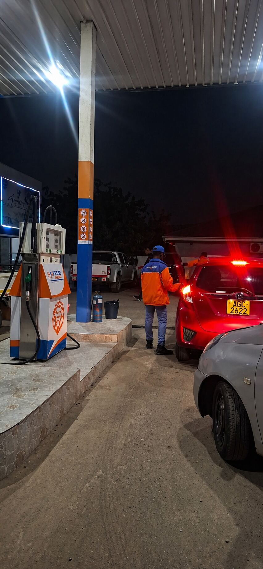 Express Energy attendant in branded orange jacket serving a customer at the pump